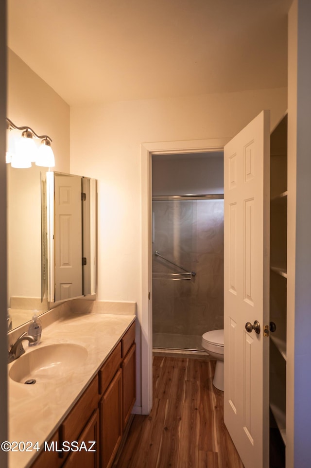 bathroom featuring hardwood / wood-style flooring, vanity, toilet, and walk in shower