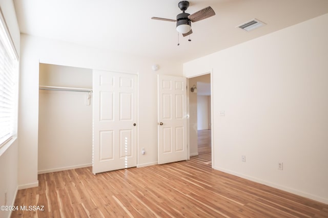 unfurnished bedroom with ceiling fan, light hardwood / wood-style floors, a closet, and multiple windows