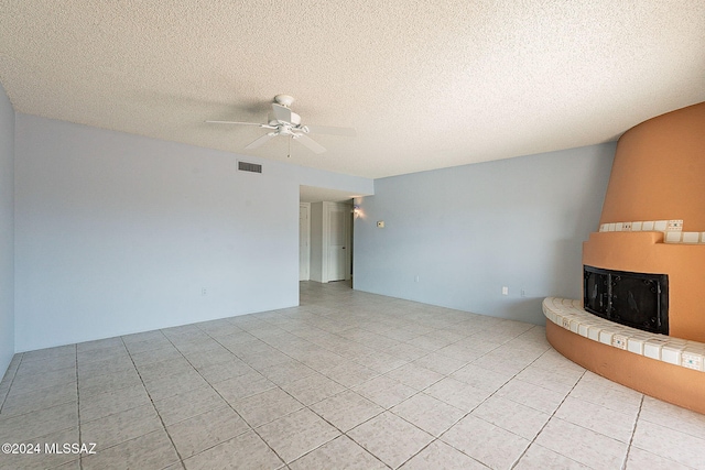 unfurnished living room featuring ceiling fan, light tile patterned flooring, and a textured ceiling