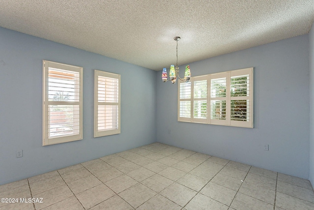 spare room with light tile patterned floors, a textured ceiling, and a chandelier