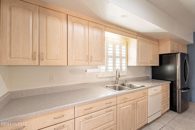 kitchen with white dishwasher, sink, stainless steel fridge, light tile patterned floors, and light brown cabinetry