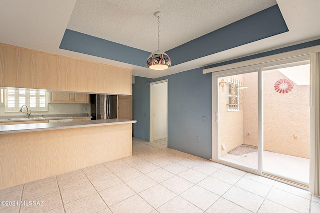 kitchen featuring stainless steel fridge, light brown cabinetry, sink, light tile patterned floors, and hanging light fixtures