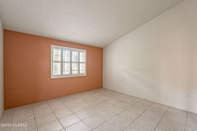 spare room featuring light tile patterned floors and a textured ceiling