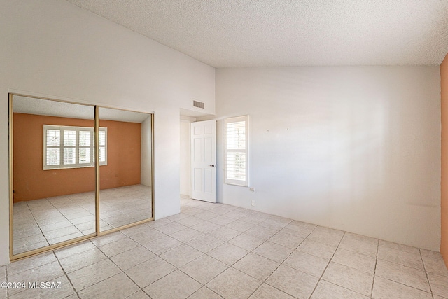 unfurnished bedroom with multiple windows, high vaulted ceiling, and a closet