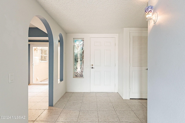 foyer entrance with light tile patterned floors and a textured ceiling