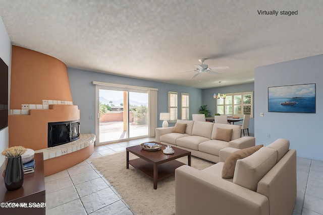 living room featuring ceiling fan, light tile patterned floors, and a textured ceiling