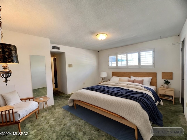 bedroom with a textured ceiling and dark carpet