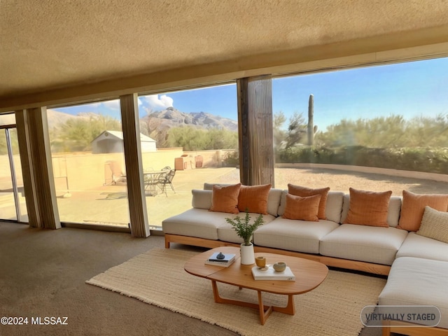 living room featuring a mountain view, carpet floors, a textured ceiling, and a wealth of natural light