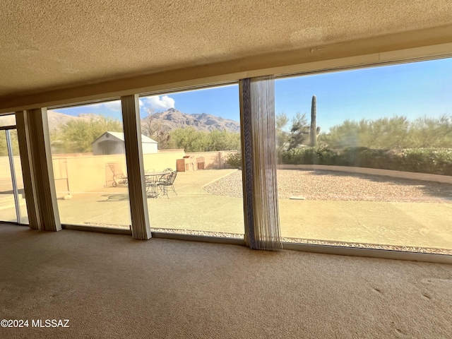 doorway to outside featuring a mountain view, carpet floors, and a textured ceiling