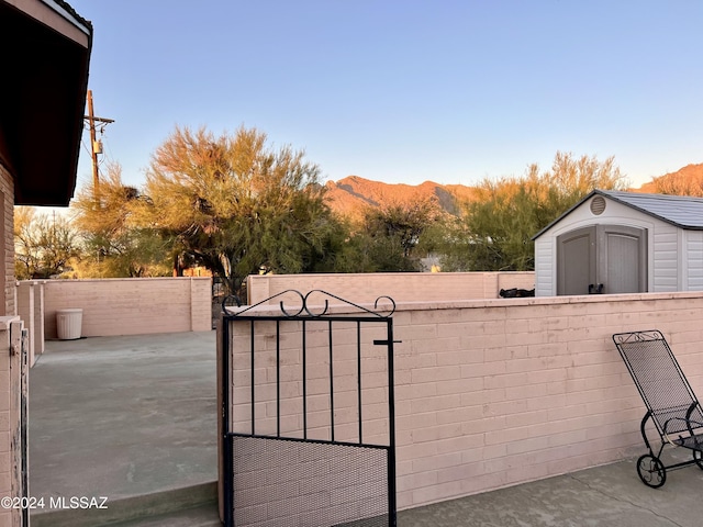 view of gate featuring a mountain view and a storage unit