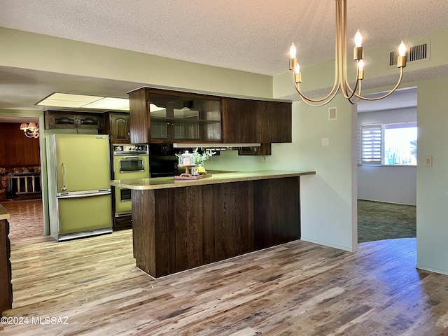 kitchen with a textured ceiling, dark brown cabinetry, light hardwood / wood-style flooring, and fridge