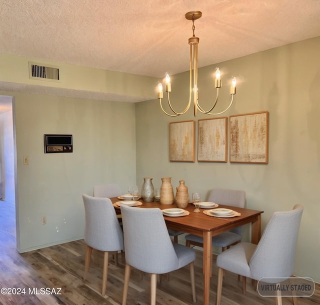 dining room featuring wood-type flooring, a textured ceiling, and a chandelier