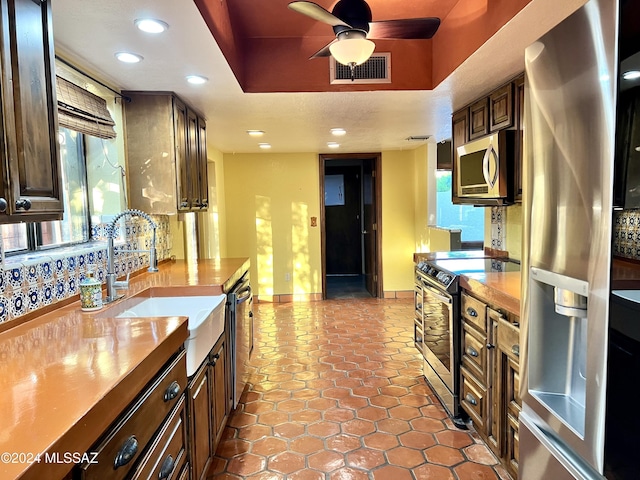 kitchen featuring ceiling fan, sink, stainless steel appliances, and dark brown cabinets