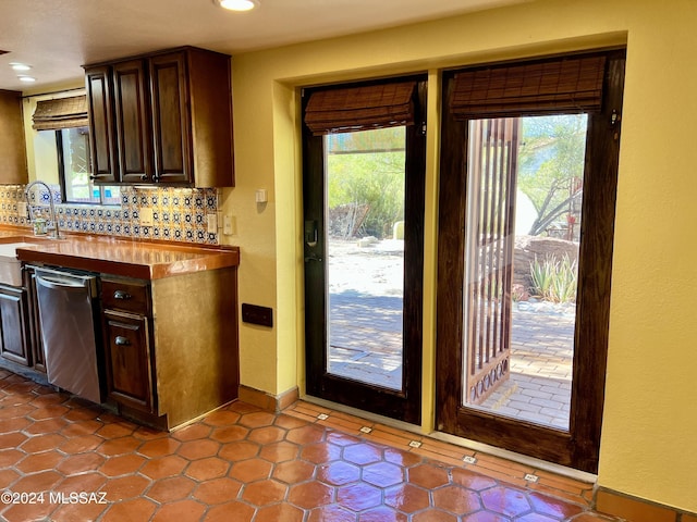 kitchen with backsplash, dark brown cabinets, a healthy amount of sunlight, and stainless steel dishwasher