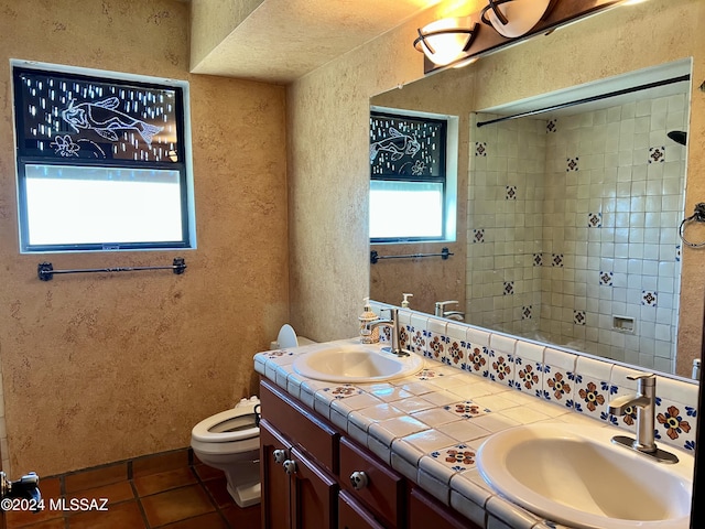 bathroom featuring a tile shower, tile patterned flooring, vanity, and toilet