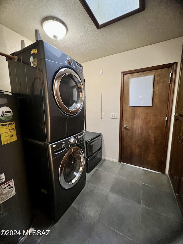 laundry room featuring a textured ceiling, a skylight, stacked washer / drying machine, and water heater