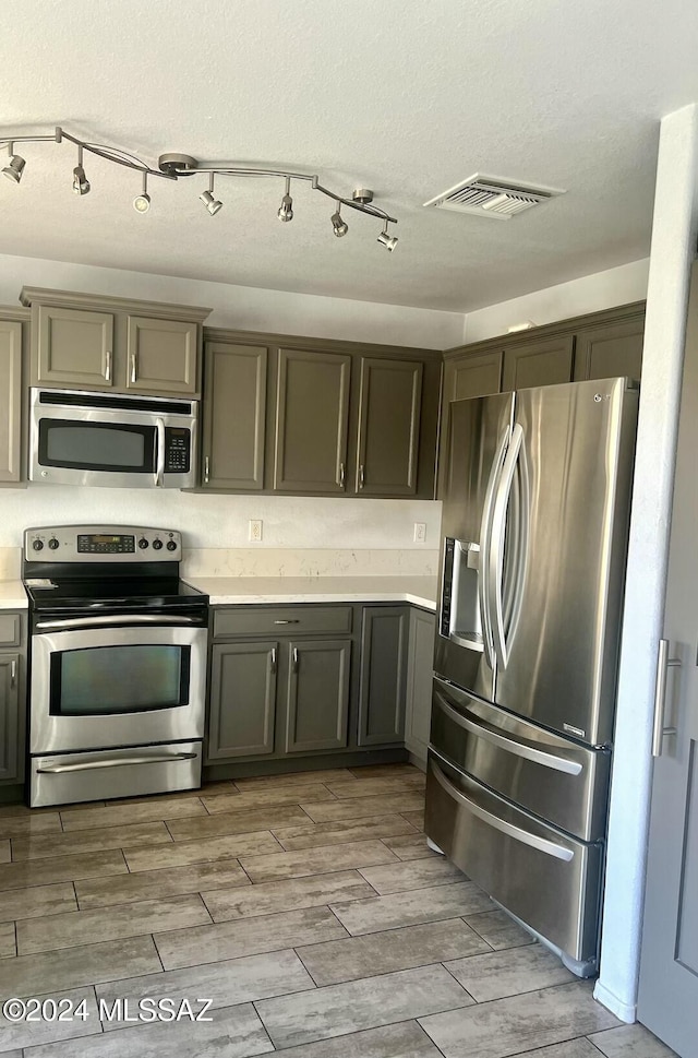 kitchen with a textured ceiling, light wood-type flooring, and stainless steel appliances