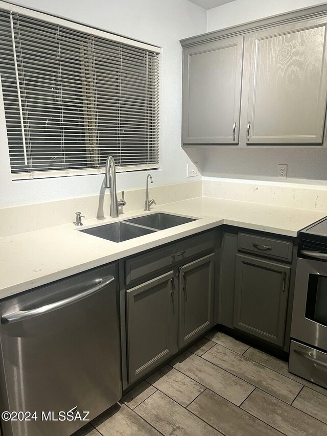 kitchen featuring gray cabinets, sink, light hardwood / wood-style flooring, and appliances with stainless steel finishes