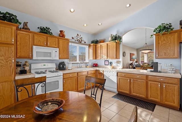 kitchen with sink, lofted ceiling, decorative light fixtures, white appliances, and light tile patterned flooring