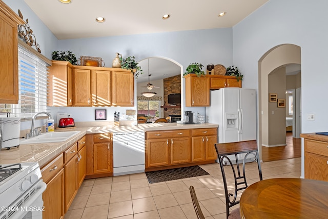 kitchen featuring lofted ceiling, white appliances, sink, and light tile patterned floors