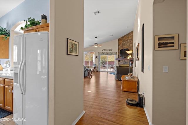 kitchen featuring ceiling fan, white fridge with ice dispenser, high vaulted ceiling, and light hardwood / wood-style flooring