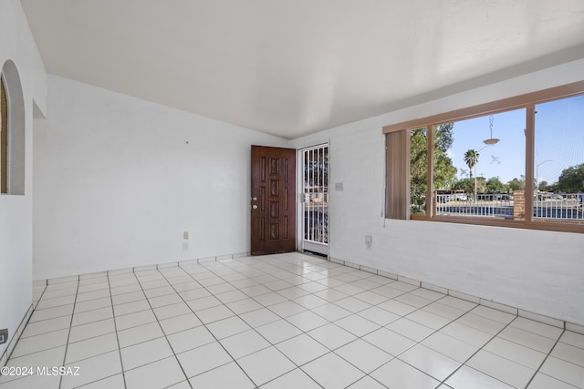 unfurnished room with lofted ceiling and light tile patterned floors