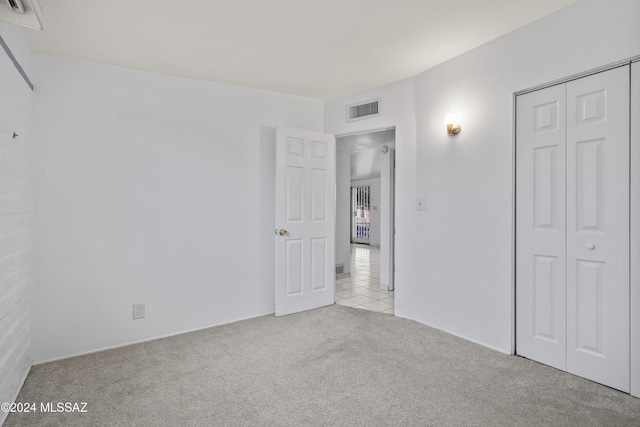 unfurnished bedroom with light carpet and a closet