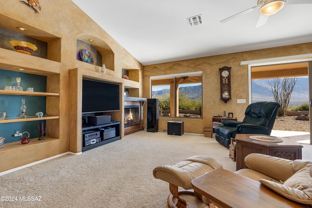 carpeted living room featuring ceiling fan, plenty of natural light, built in shelves, and vaulted ceiling