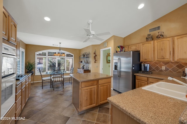 kitchen featuring ceiling fan, a center island, pendant lighting, stainless steel refrigerator with ice dispenser, and sink