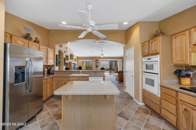 kitchen featuring a center island, sink, light brown cabinetry, double oven, and stainless steel fridge