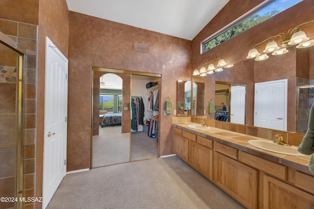 bathroom featuring ceiling fan, vanity, and walk in shower