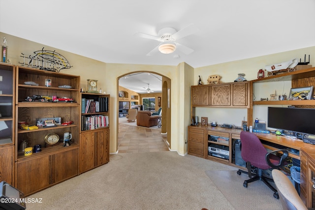 carpeted office with ceiling fan and built in desk