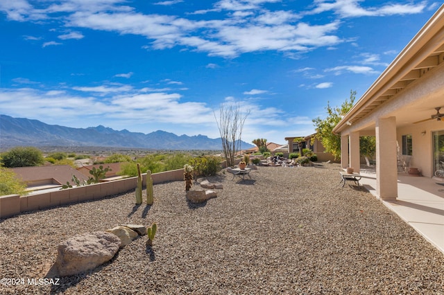 view of yard with ceiling fan, a patio area, and a mountain view