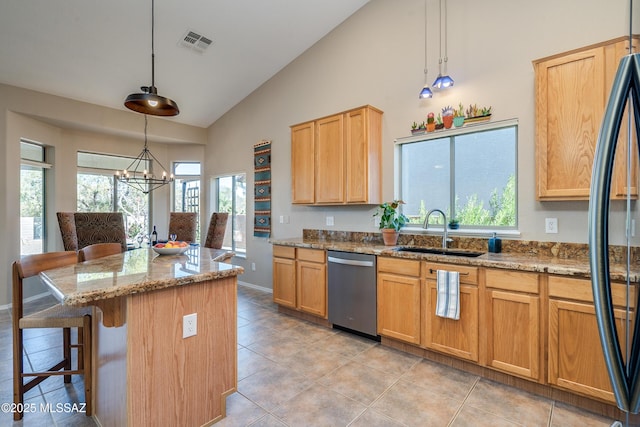 kitchen with black fridge, stainless steel dishwasher, light stone counters, pendant lighting, and a chandelier