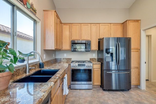 kitchen with sink, light tile patterned floors, light stone countertops, light brown cabinetry, and appliances with stainless steel finishes