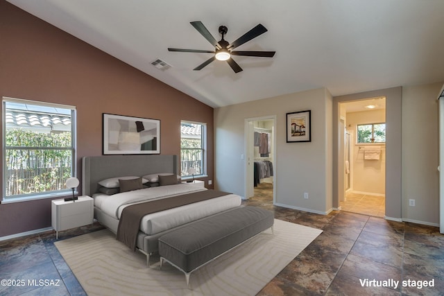 bedroom with ceiling fan, lofted ceiling, multiple windows, and ensuite bath