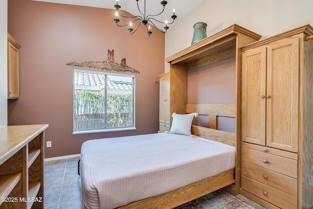 bedroom featuring an inviting chandelier, vaulted ceiling, and dark tile patterned floors