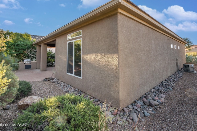 view of side of home with area for grilling, a patio, and central air condition unit