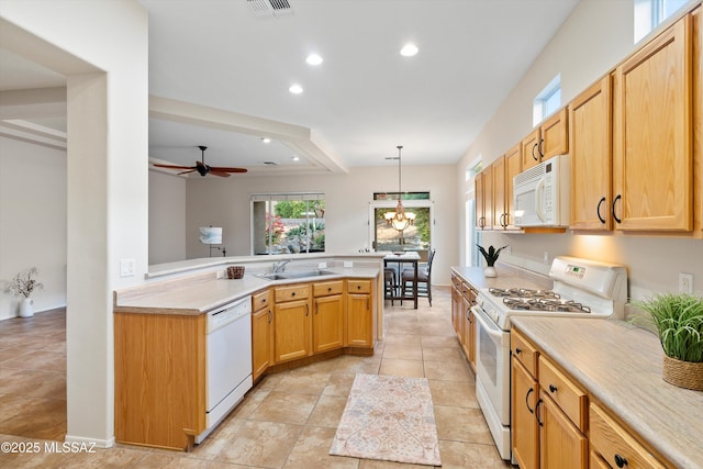 kitchen with sink, white appliances, kitchen peninsula, ceiling fan with notable chandelier, and pendant lighting