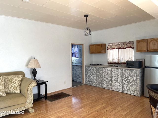 kitchen with stainless steel refrigerator, sink, hanging light fixtures, and wood-type flooring