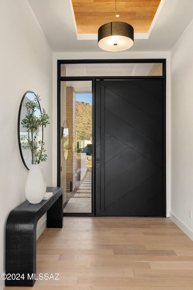 entryway with a tray ceiling, light hardwood / wood-style floors, and wood ceiling