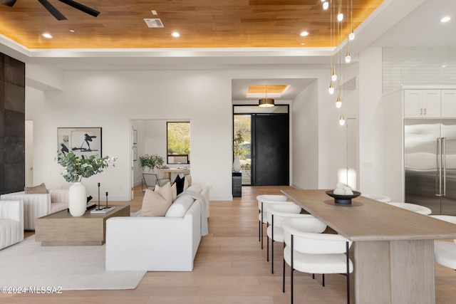living room featuring ceiling fan, light hardwood / wood-style floors, a raised ceiling, and wood ceiling