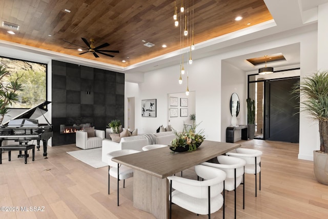 dining area with a tray ceiling, ceiling fan, wooden ceiling, and light hardwood / wood-style floors