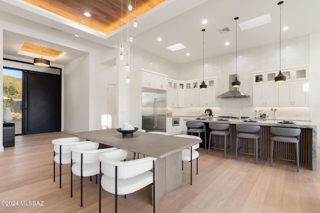 dining room with a tray ceiling, light hardwood / wood-style flooring, and wooden ceiling
