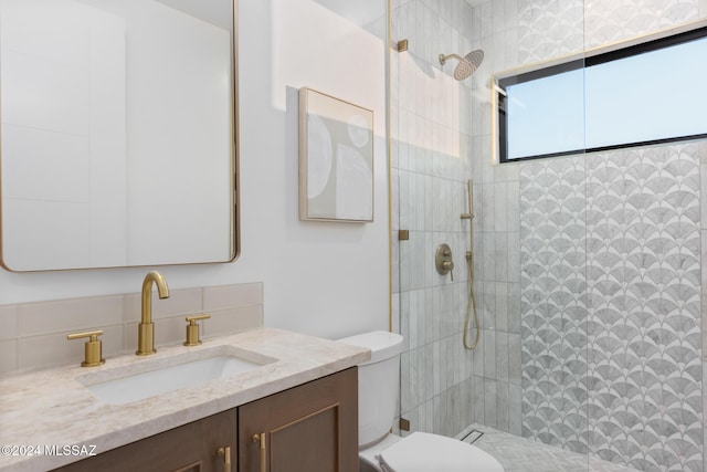 bathroom with tiled shower, vanity, and toilet