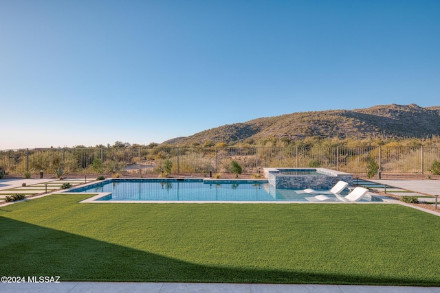 view of swimming pool featuring a mountain view, an outdoor hot tub, and a lawn