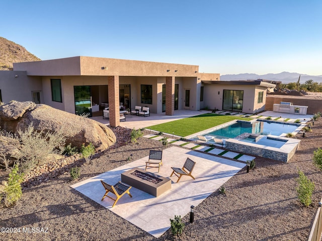 view of swimming pool with an in ground hot tub, an outdoor living space with a fire pit, a patio area, a mountain view, and a yard
