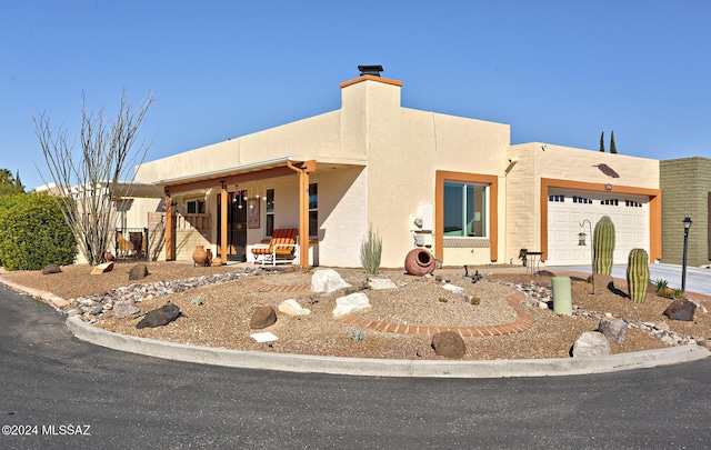 pueblo-style house featuring covered porch and a garage