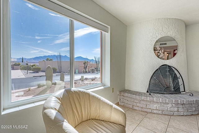 living room with a mountain view, a wealth of natural light, tile patterned floors, and a brick fireplace