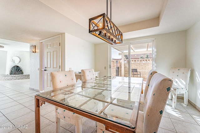 dining space featuring a brick fireplace and light tile patterned flooring